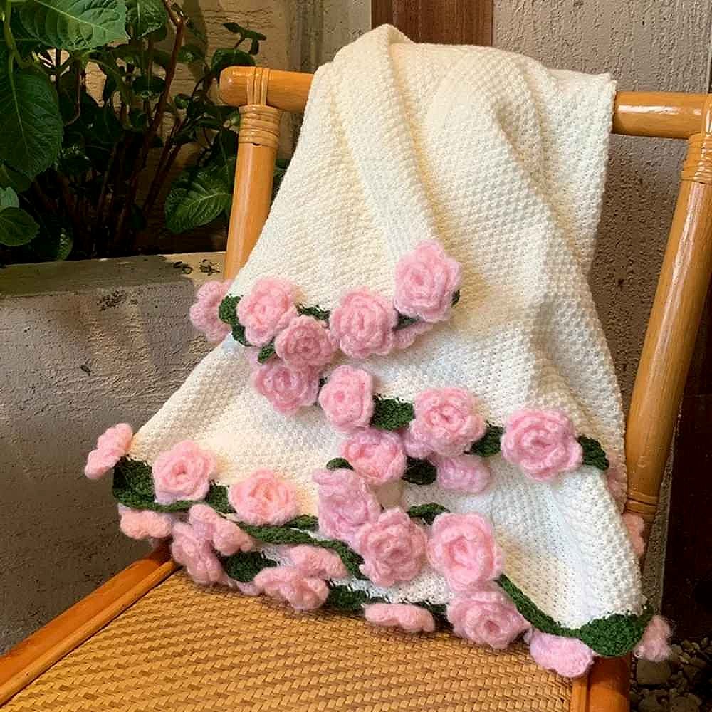 Crochet rose baby blanket draped over a nursery chair — close-up of dimensional rose detail